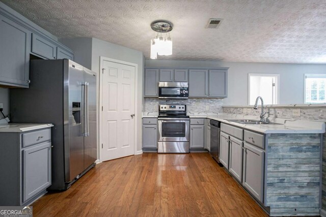 2482 Brittany Park Ln, Ellenwood, GA 30294 - kitchen featuring appliances with stainless steel finishes, a sink, gray cabinetry, dark wood-style flooring, and light countertops