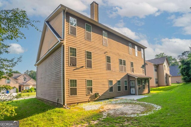 2482 Brittany Park Ln, Ellenwood, GA 30294 - back of house with a chimney, a lawn, a patio, and a sunroom