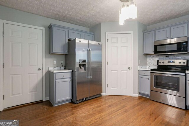 2482 Brittany Park Ln, Ellenwood, GA 30294 - kitchen with appliances with stainless steel finishes, gray cabinets, light wood-style floors, light countertops, and backsplash