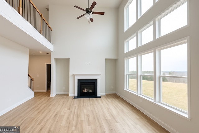 3468 Jasmine Way SW, South Fulton, GA 30331 - unfurnished living room with a towering ceiling, a ceiling fan, light wood-type flooring, stairs, and baseboards