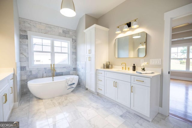 982 Wildberry Ct, Jefferson, GA 30549 - bathroom with vanity, marble look tiles, a freestanding tub, tile walls, and lofted ceiling