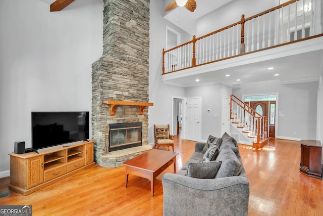 242 Pristine Cv, Hartwell, GA 30643 - living room featuring a high ceiling, stairway, light wood finished floors, a stone fireplace, and baseboards