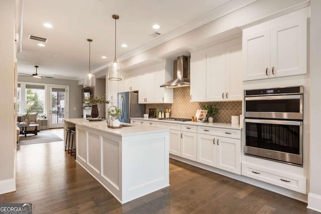 6613 Encore Blvd, Atlanta, GA 30328 - kitchen featuring wall chimney exhaust hood, stainless steel appliances, white cabinets, decorative backsplash, and light countertops