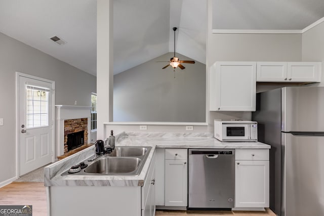 305 Overland Trl, Temple, GA 30179 - kitchen featuring appliances with stainless steel finishes, a peninsula, a sink, white cabinets, and lofted ceiling