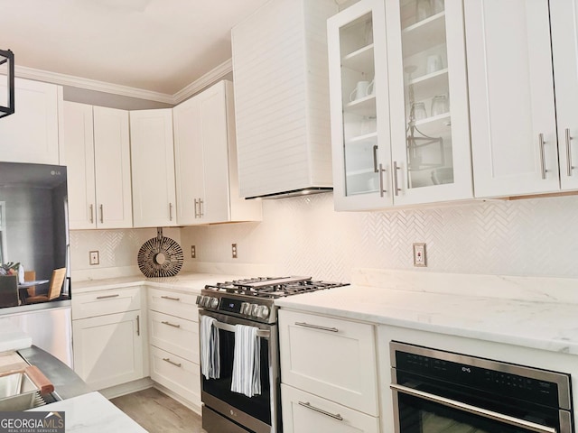 4867 Pinnacle Dr, Stone Mountain, GA 30088 - kitchen with stainless steel range with gas stovetop, oven, white cabinetry, and crown molding