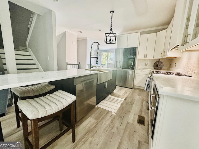 4867 Pinnacle Dr, Stone Mountain, GA 30088 - kitchen with stainless steel dishwasher, white cabinetry, light wood-style flooring, light countertops, and a sink