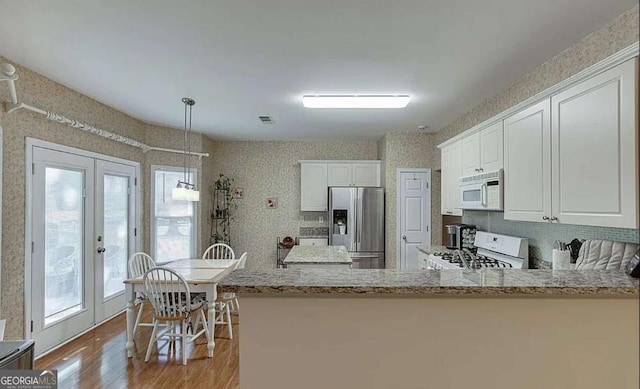 1008 Post Horn Run, Lawrenceville, GA 30045 - kitchen with white appliances, healthy amount of natural light, wood finished floors, white cabinetry, and wallpapered walls