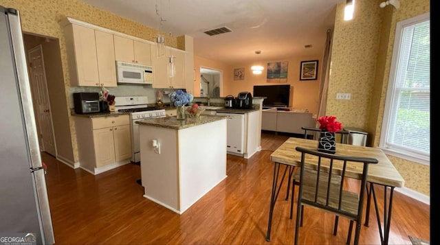 1008 Post Horn Run, Lawrenceville, GA 30045 - kitchen with white appliances, a peninsula, dark wood-type flooring, wallpapered walls, and healthy amount of natural light
