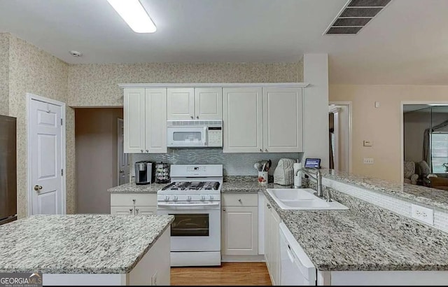 1008 Post Horn Run, Lawrenceville, GA 30045 - kitchen featuring white appliances, a peninsula, white cabinetry, light wood finished floors, and light stone countertops