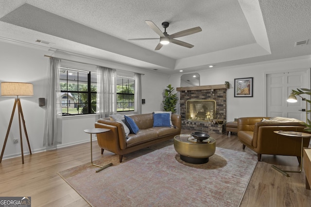 107 Rose Dhu Way, Savannah, GA 31419 - living area with a textured ceiling, ceiling fan, light wood-style flooring, a tray ceiling, and a brick fireplace