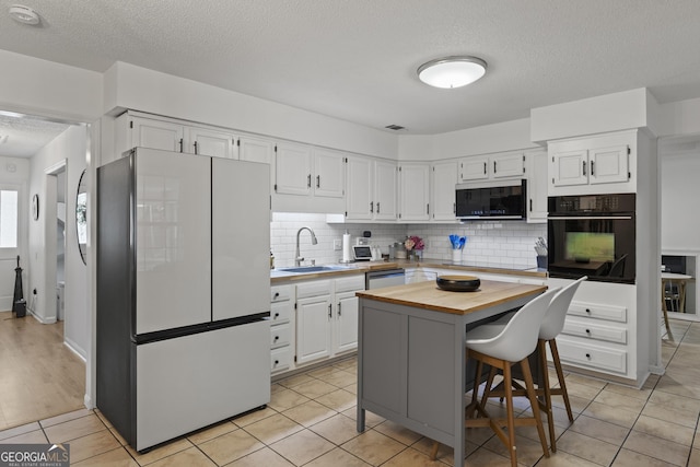 107 Rose Dhu Way, Savannah, GA 31419 - kitchen with black appliances, a sink, wooden counters, a textured ceiling, and white cabinetry