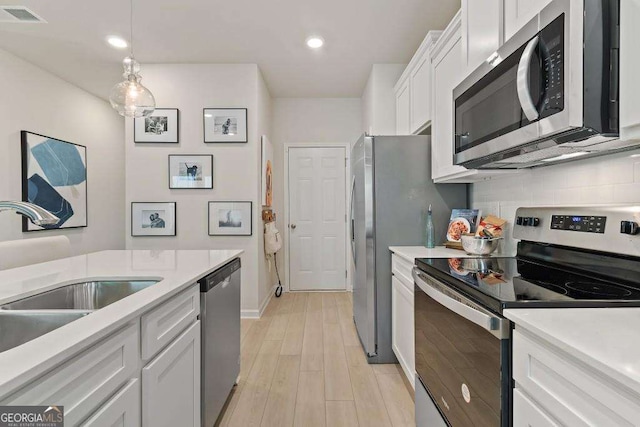 377 Navigator Ln, Mcdonough, GA 30253 - kitchen featuring appliances with stainless steel finishes, a sink, white cabinetry, decorative backsplash, and light wood-style flooring