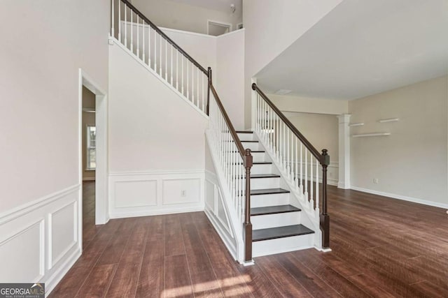 153 Towey Trl, Woodstock, GA 30188 - staircase with wood finished floors, a towering ceiling, a wainscoted wall, and a decorative wall
