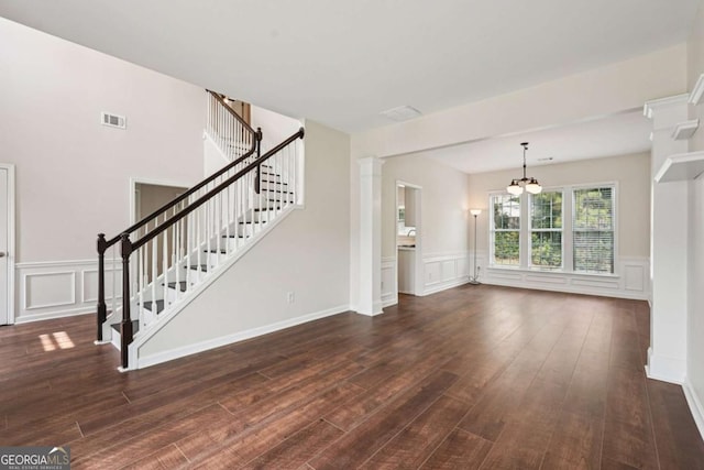 153 Towey Trl, Woodstock, GA 30188 - unfurnished living room with a decorative wall, stairway, wood finished floors, a chandelier, and a wainscoted wall