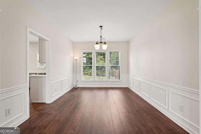 153 Towey Trl, Woodstock, GA 30188 - unfurnished dining area featuring a chandelier, a decorative wall, a wainscoted wall, and dark wood-style flooring