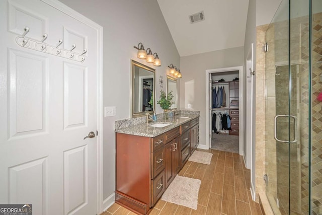 1409 Echo Mill Dr, Powder Springs, GA 30127 - bathroom featuring vaulted ceiling, double vanity, a stall shower, a walk in closet, and wood tiled floors