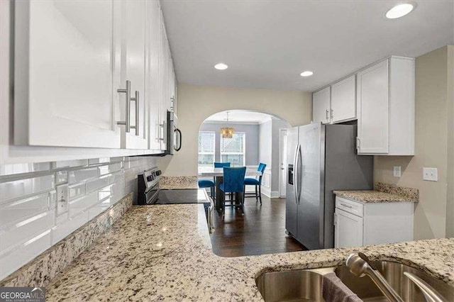 5880 Garden Cir, Douglasville, GA 30135 - kitchen with arched walkways, appliances with stainless steel finishes, white cabinets, dark wood-style floors, and backsplash