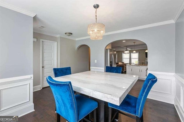 5880 Garden Cir, Douglasville, GA 30135 - dining room with arched walkways, a chandelier, dark wood-type flooring, crown molding, and a wainscoted wall