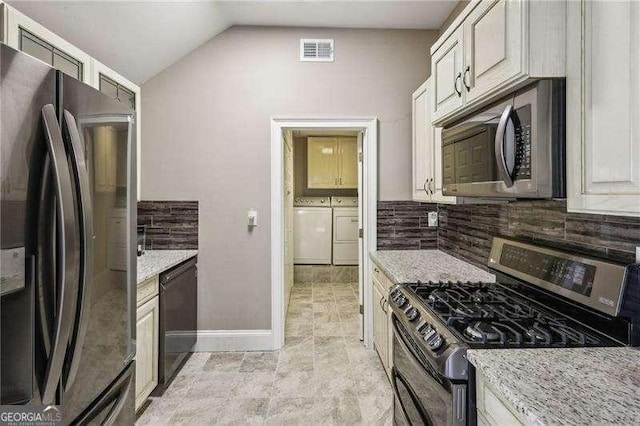 511 Pine Valley Rd SE, Marietta, GA 30067 - kitchen featuring appliances with stainless steel finishes, decorative backsplash, washer and clothes dryer, lofted ceiling, and light stone counters