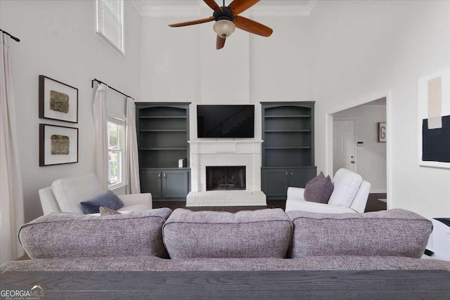 2820 Channing Way, Cumming, GA 30040 - living room featuring a high ceiling, a ceiling fan, crown molding, a brick fireplace, and built in shelves