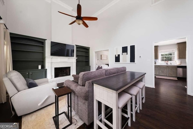 2820 Channing Way, Cumming, GA 30040 - living room with dark wood-style flooring, a ceiling fan, a towering ceiling, baseboards, and a brick fireplace