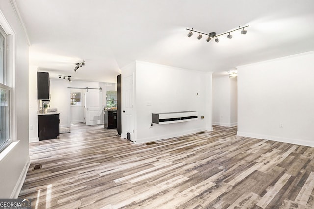 2674 Skylane Dr, Marietta, GA 30062 - unfurnished living room featuring a barn door, track lighting, light wood-style flooring, and ornamental molding