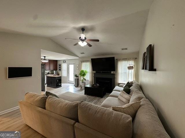 298 Timberwind Dr, Byron, GA 31008 - living area with a ceiling fan, vaulted ceiling, light wood finished floors, a fireplace, and baseboards