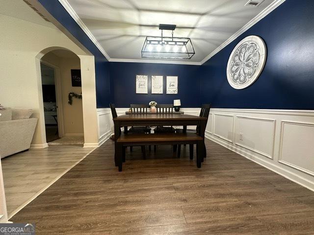 298 Timberwind Dr, Byron, GA 31008 - dining area with arched walkways, ornamental molding, wood finished floors, a wainscoted wall, and a decorative wall