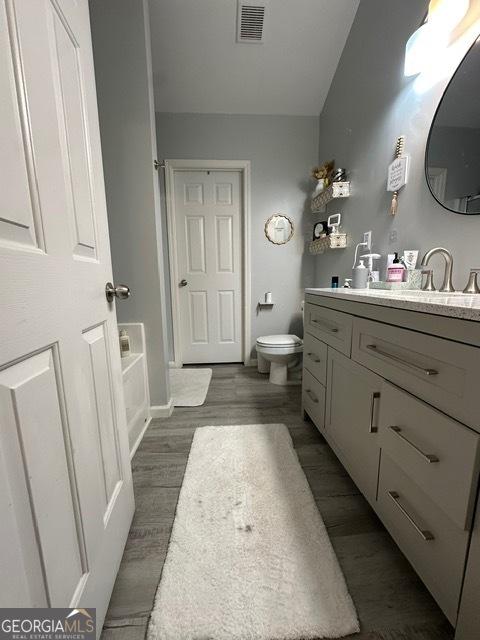298 Timberwind Dr, Byron, GA 31008 - full bath featuring vanity, wood finished floors, toilet, a tub to relax in, and baseboards