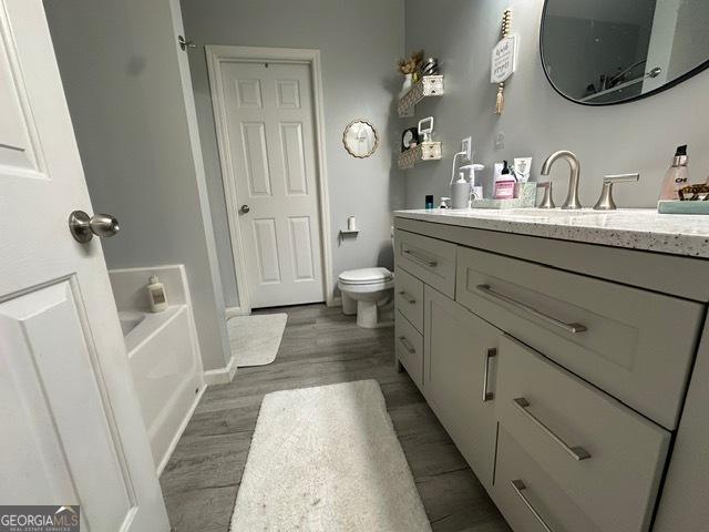 298 Timberwind Dr, Byron, GA 31008 - bathroom with vanity, wood finished floors, a bath, toilet, and baseboards