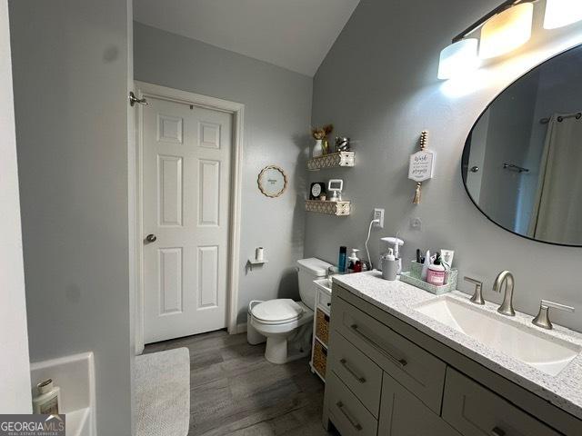 298 Timberwind Dr, Byron, GA 31008 - bathroom featuring vanity, toilet, wood finished floors, lofted ceiling, and a shower with shower curtain
