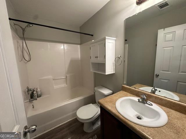 298 Timberwind Dr, Byron, GA 31008 - bathroom with toilet, vanity, washtub / shower combination, and wood finished floors