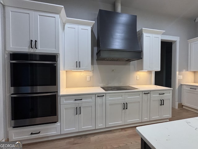 5680 Mack Way, Gainesville, GA 30506 - kitchen with custom exhaust hood, stainless steel double oven, black electric stovetop, light wood-style flooring, and light countertops