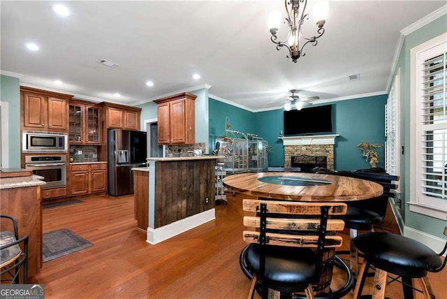 1132 Ivey Brook Dr, Bethlehem, GA 30620 - kitchen featuring appliances with stainless steel finishes, brown cabinets, ceiling fan, backsplash, and ornamental molding