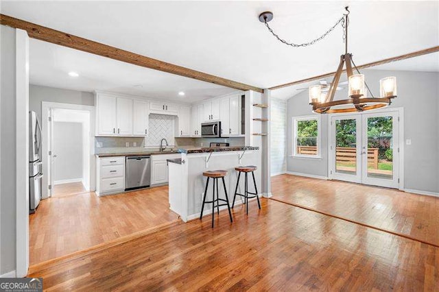 3274 Ridgecrest Rd SE, Smyrna, GA 30080 - kitchen with stainless steel appliances, a chandelier, light wood-type flooring, a breakfast bar, and beamed ceiling