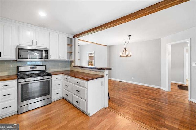 3274 Ridgecrest Rd SE, Smyrna, GA 30080 - kitchen with appliances with stainless steel finishes, a chandelier, a peninsula, white cabinetry, and tasteful backsplash