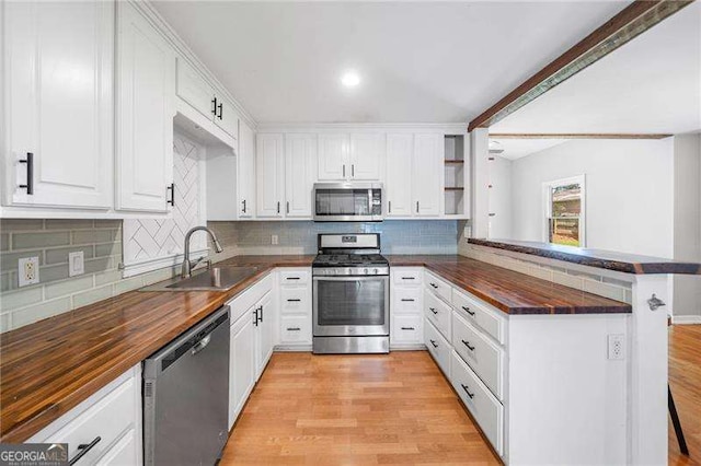 3274 Ridgecrest Rd SE, Smyrna, GA 30080 - kitchen featuring appliances with stainless steel finishes, a sink, wooden counters, a peninsula, and white cabinetry