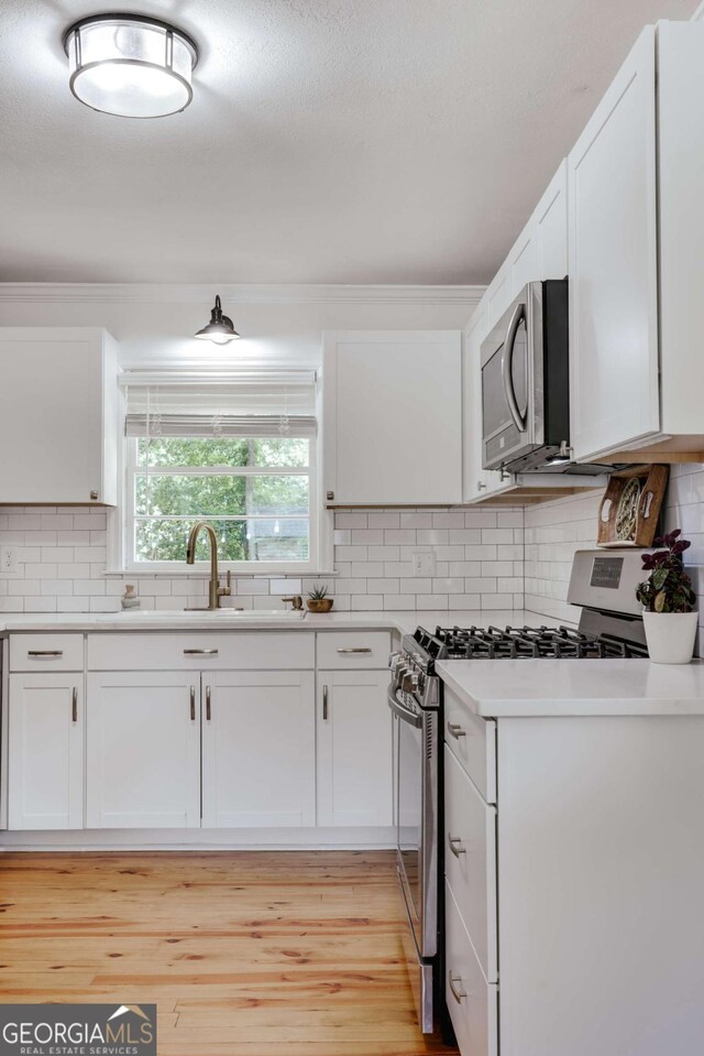 980 Oglethorpe Ave, Athens, GA 30606 - kitchen with appliances with stainless steel finishes, white cabinets, decorative backsplash, and crown molding