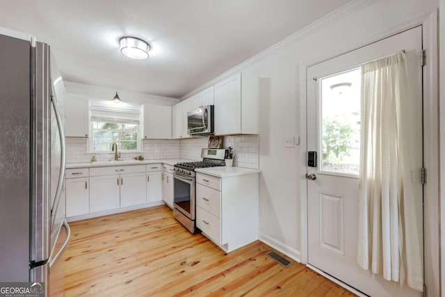 980 Oglethorpe Ave, Athens, GA 30606 - kitchen with appliances with stainless steel finishes, light wood-style flooring, tasteful backsplash, light countertops, and white cabinets