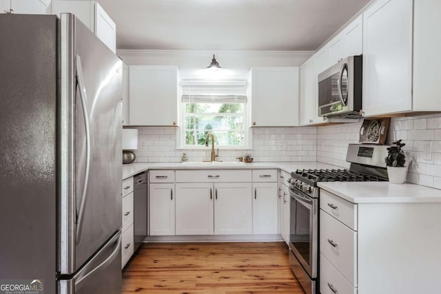 980 Oglethorpe Ave, Athens, GA 30606 - kitchen with stainless steel appliances, ornamental molding, light wood finished floors, and white cabinetry