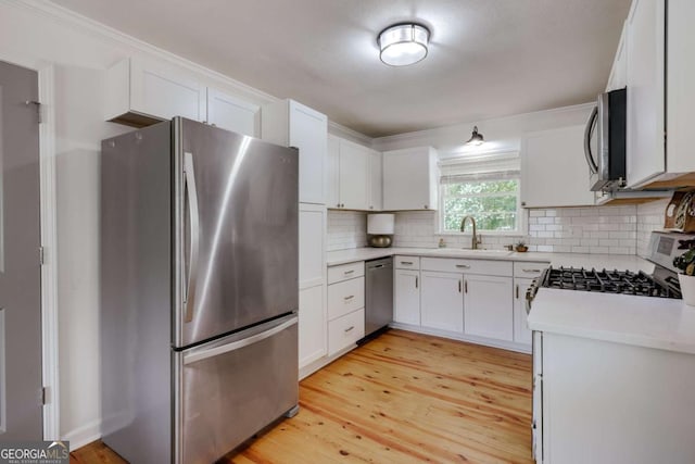 980 Oglethorpe Ave, Athens, GA 30606 - kitchen with stainless steel appliances, a sink, light wood-style floors, light countertops, and tasteful backsplash