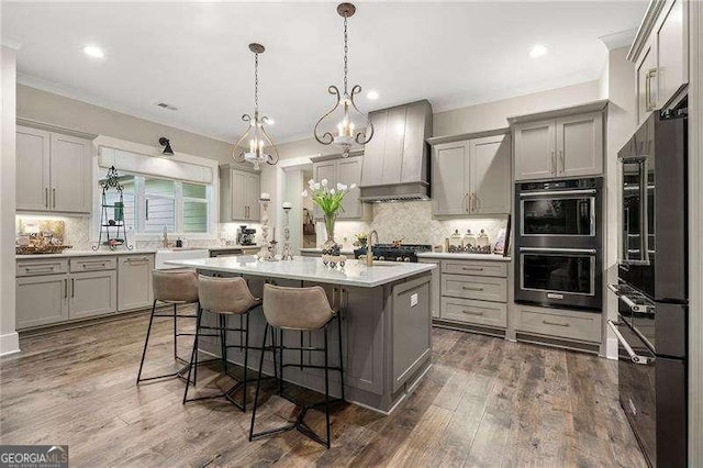 131 Forsyth Park Ln, Woodstock, GA 30188 - kitchen with custom exhaust hood, gray cabinetry, a breakfast bar, backsplash, and ornamental molding