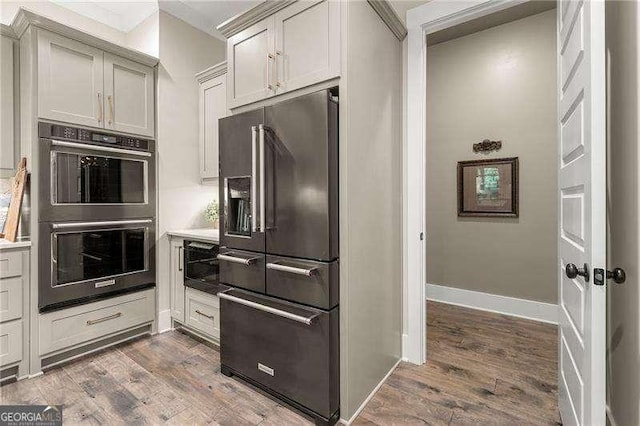 131 Forsyth Park Ln, Woodstock, GA 30188 - kitchen with high end fridge, stainless steel double oven, dark wood-style flooring, baseboards, and light countertops