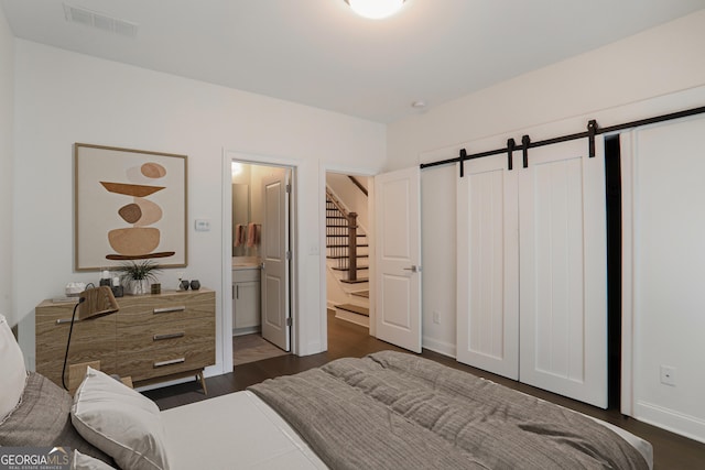 4202 Deming Cir, Sandy Springs, GA 30342 - bedroom featuring a barn door, dark wood-style floors, and connected bathroom