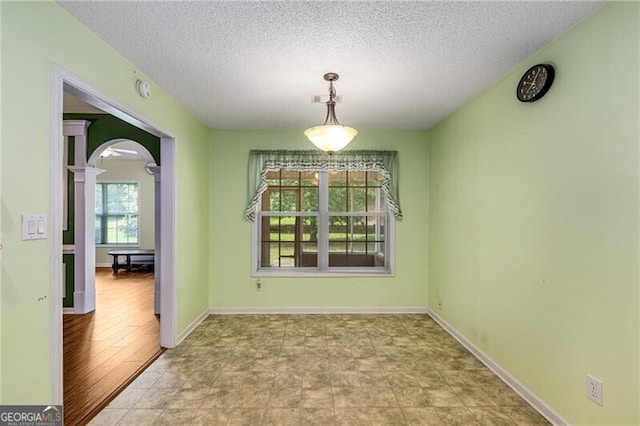 115 Pinnacle Ln, Mcdonough, GA 30253 - unfurnished dining area featuring decorative columns, arched walkways, a textured ceiling, and baseboards