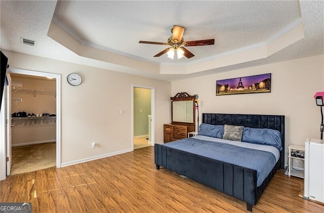 115 Pinnacle Ln, Mcdonough, GA 30253 - bedroom featuring a raised ceiling, crown molding, a textured ceiling, light wood-type flooring, and a walk in closet