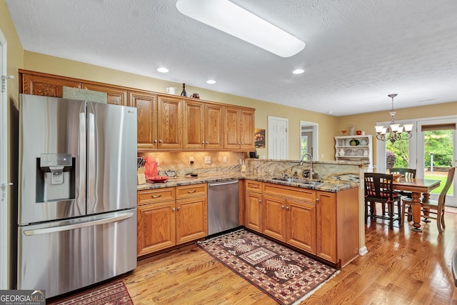 70 Merion Way, Newnan, GA 30265 - kitchen featuring stainless steel appliances, a sink, brown cabinetry, a textured ceiling, and a peninsula
