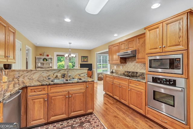 70 Merion Way, Newnan, GA 30265 - kitchen with appliances with stainless steel finishes, a sink, light wood-type flooring, under cabinet range hood, and a chandelier