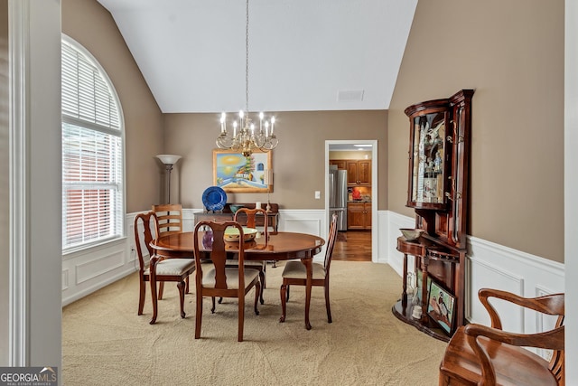70 Merion Way, Newnan, GA 30265 - carpeted dining room featuring a chandelier, vaulted ceiling, a decorative wall, and wainscoting