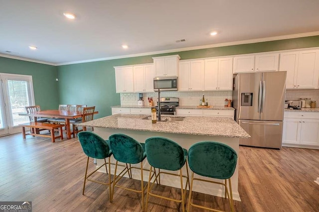 6827 Chataran Dr, Lithia Springs, GA 30122 - kitchen with stainless steel appliances, a sink, backsplash, light wood-type flooring, and white cabinetry